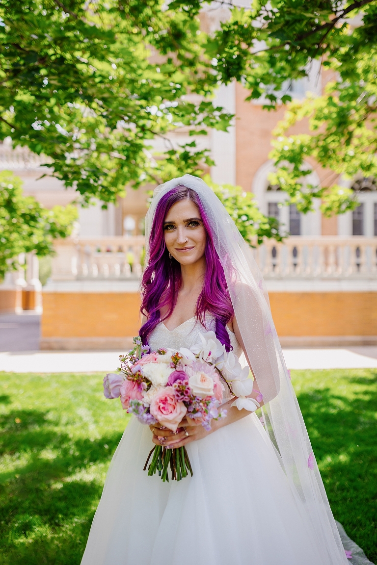 bride with purple hair standing under trees